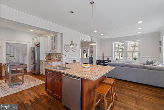 kitchen featuring a sink, stainless steel appliances, a breakfast bar area, glass insert cabinets, and dark wood-style flooring