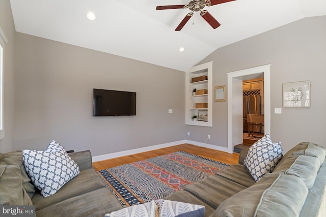 living room with lofted ceiling, light wood-style floors, and baseboards