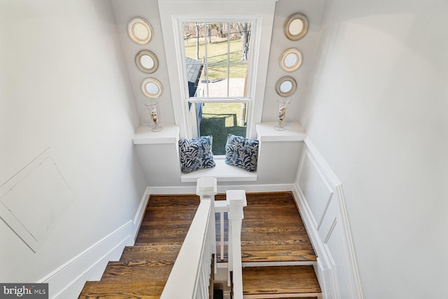 staircase featuring wood finished floors and baseboards