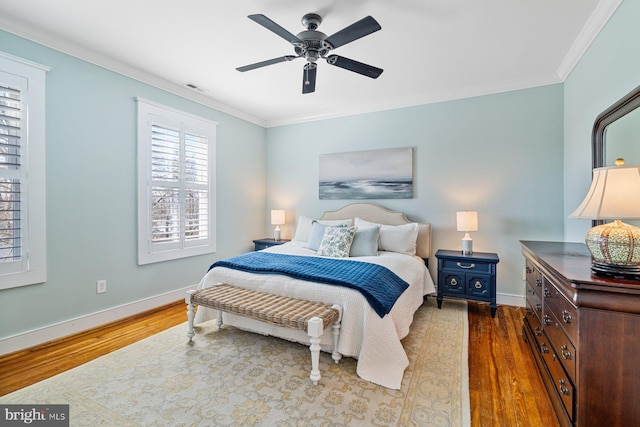 bedroom with visible vents, baseboards, wood finished floors, and crown molding