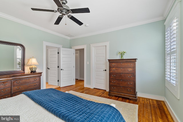 bedroom with multiple windows, baseboards, wood finished floors, and ornamental molding