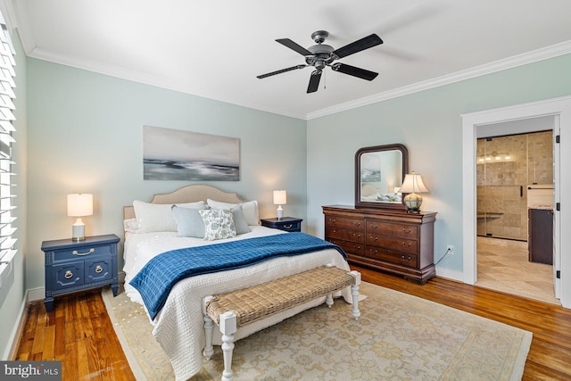 bedroom featuring wood finished floors, baseboards, ensuite bath, ornamental molding, and multiple windows