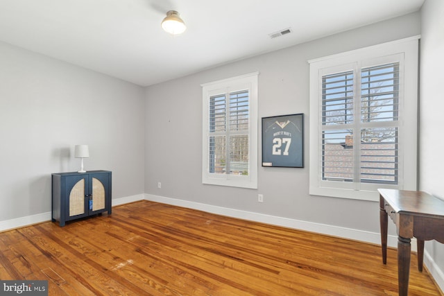 spare room with a wealth of natural light, baseboards, and wood finished floors