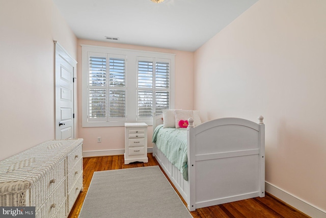 bedroom with visible vents, baseboards, and wood finished floors