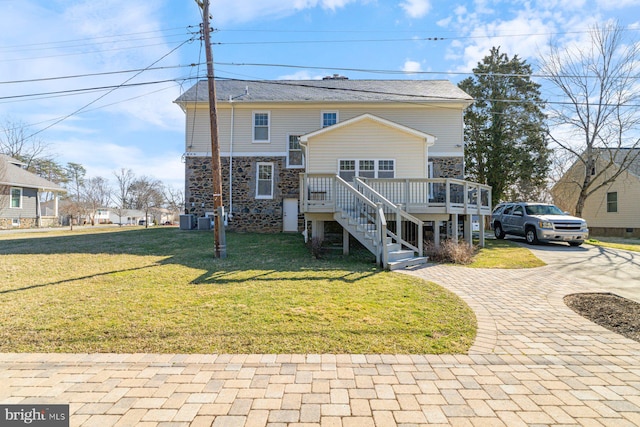 view of front facade with a front lawn, stairs, central AC, a deck, and stone siding