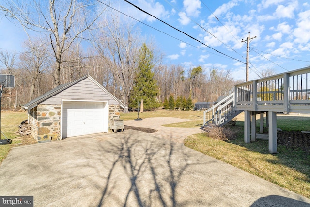 exterior space featuring an outbuilding, stairway, concrete driveway, a deck, and a detached garage