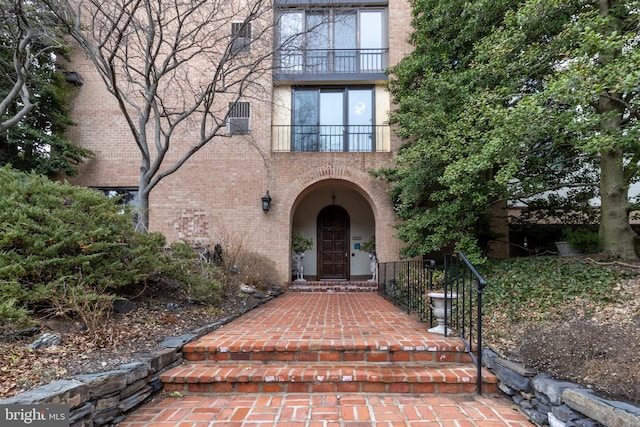 property entrance featuring brick siding, cooling unit, and a balcony