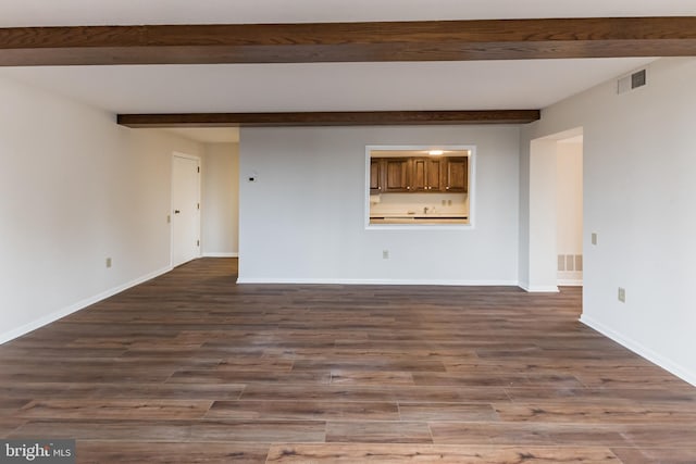 spare room with baseboards, visible vents, dark wood-style flooring, and beamed ceiling