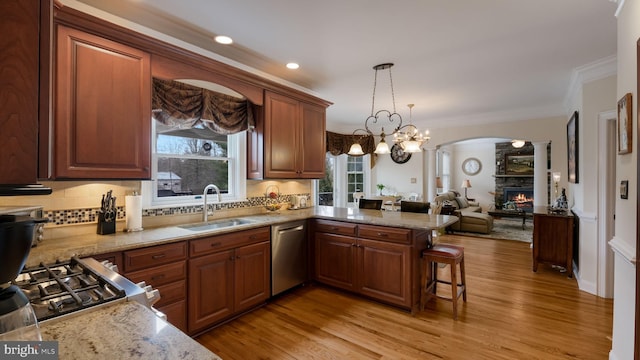 kitchen featuring dishwasher, open floor plan, crown molding, a fireplace, and a sink