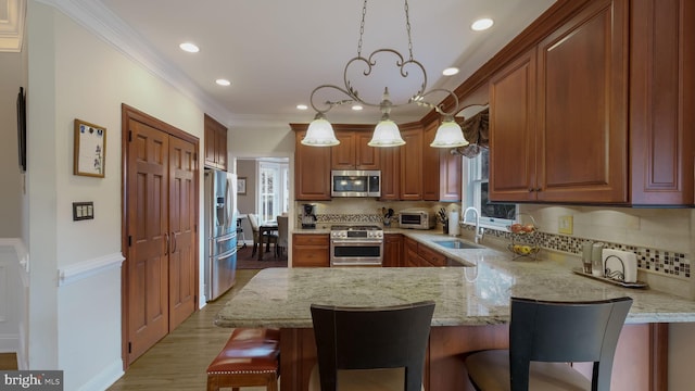 kitchen with stainless steel appliances, a healthy amount of sunlight, a sink, a peninsula, and a kitchen bar