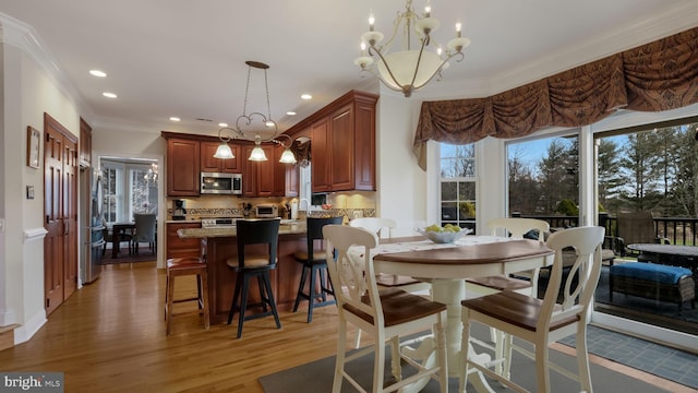 dining room featuring light wood finished floors, a chandelier, crown molding, and recessed lighting