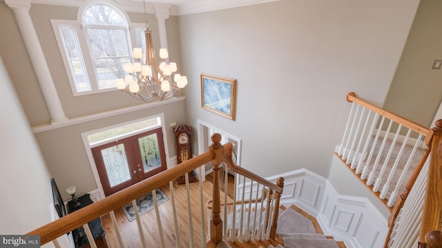 foyer featuring a notable chandelier, wood finished floors, stairs, french doors, and ornamental molding