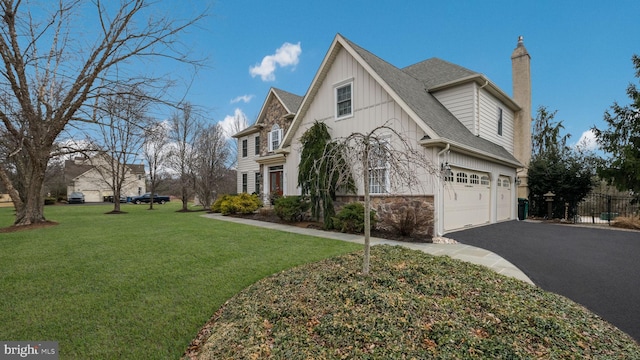 view of property exterior featuring a garage, stone siding, a chimney, aphalt driveway, and a yard