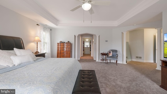 carpeted bedroom featuring arched walkways, a tray ceiling, visible vents, and decorative columns