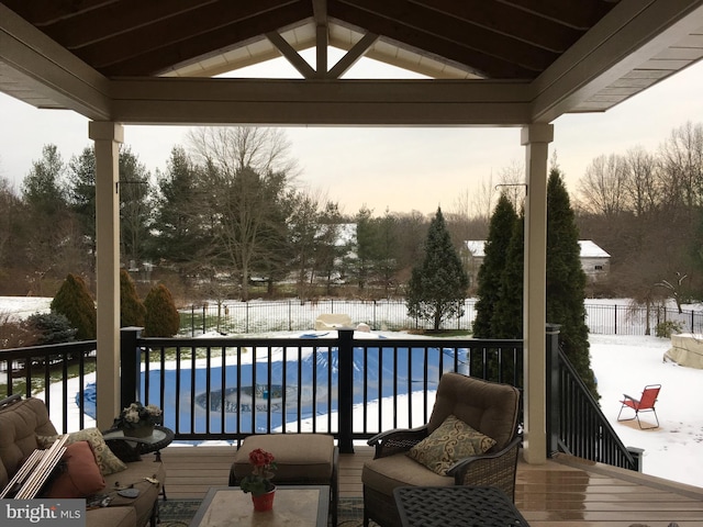 snow covered deck with fence and a fenced in pool