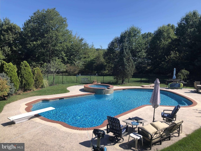 view of swimming pool featuring a pool with connected hot tub, fence, and a patio