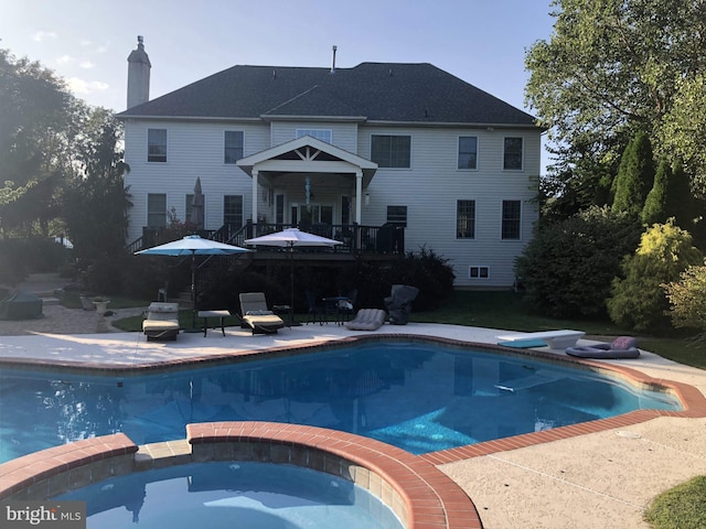 view of swimming pool with a deck, a diving board, a patio area, and a pool with connected hot tub