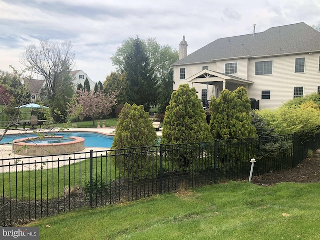 view of swimming pool with a pool with connected hot tub, fence, and a lawn