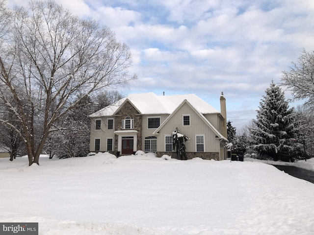 view of front of home with stone siding, a chimney, and board and batten siding