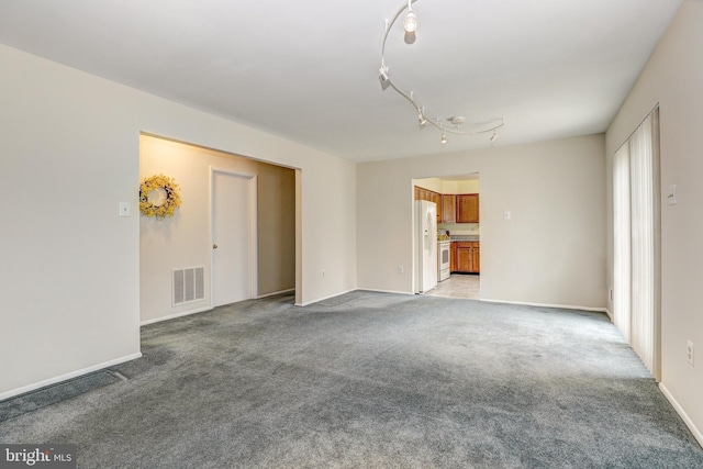 spare room with visible vents, baseboards, light colored carpet, and rail lighting