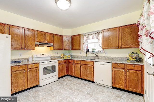 kitchen featuring under cabinet range hood, white appliances, brown cabinetry, and a sink