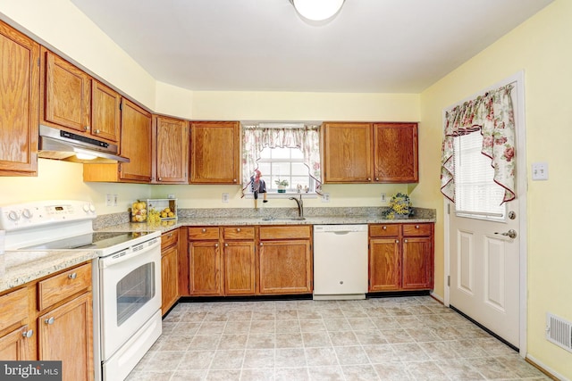 kitchen featuring under cabinet range hood, white appliances, brown cabinets, and a sink