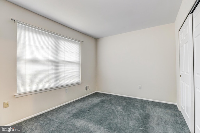 empty room with visible vents, baseboards, and dark colored carpet