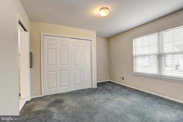 unfurnished bedroom featuring a closet, baseboards, visible vents, and dark colored carpet