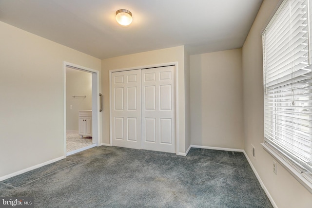 unfurnished bedroom with baseboards, a closet, and dark colored carpet