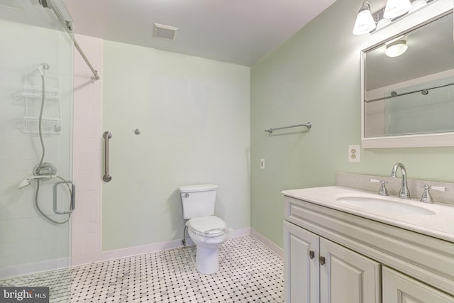 bathroom with vanity, toilet, baseboards, and a tile shower