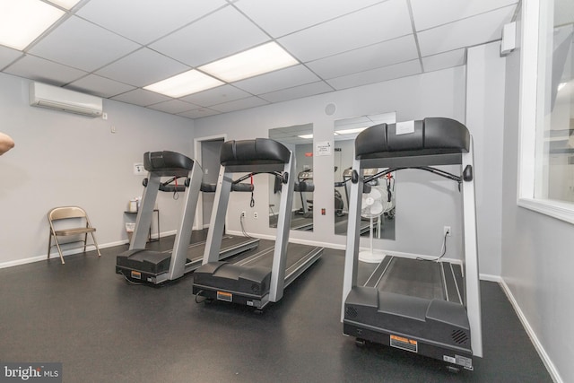 gym featuring a drop ceiling, baseboards, and a wall unit AC