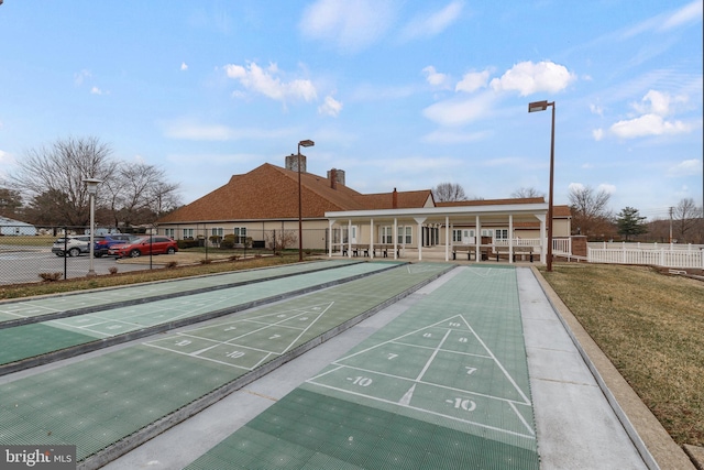 surrounding community with shuffleboard, fence, and a lawn