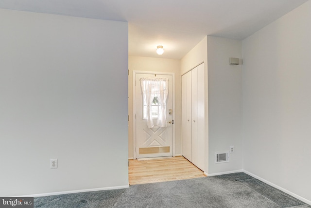 entryway with visible vents, light colored carpet, and baseboards