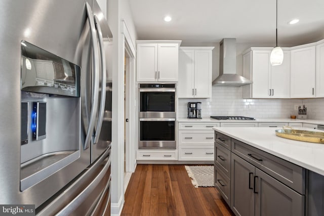 kitchen featuring backsplash, dark wood-style floors, stainless steel appliances, wall chimney exhaust hood, and light countertops