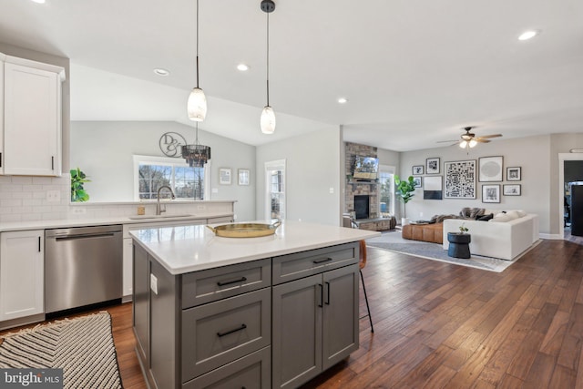 kitchen with white cabinetry, a fireplace, gray cabinets, a sink, and dishwasher