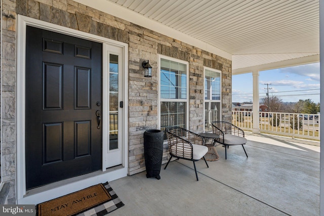 property entrance with stone siding and a porch