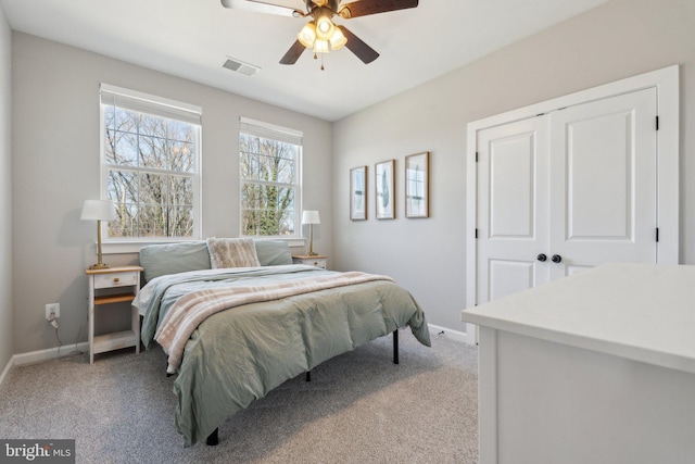 bedroom with visible vents, baseboards, light colored carpet, a closet, and a ceiling fan