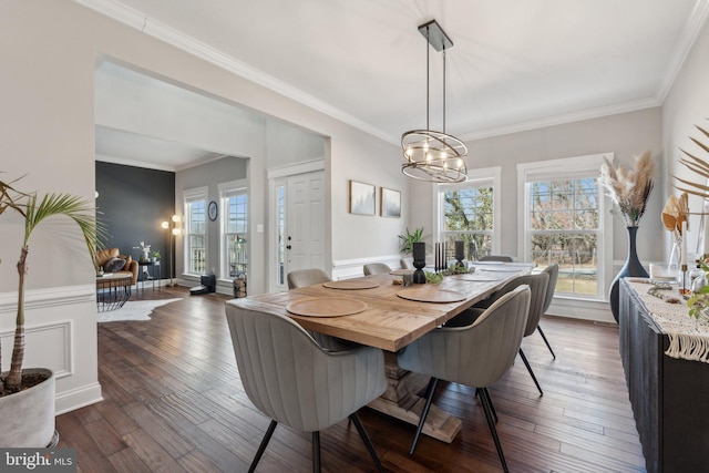 dining space with dark wood finished floors, a chandelier, and ornamental molding