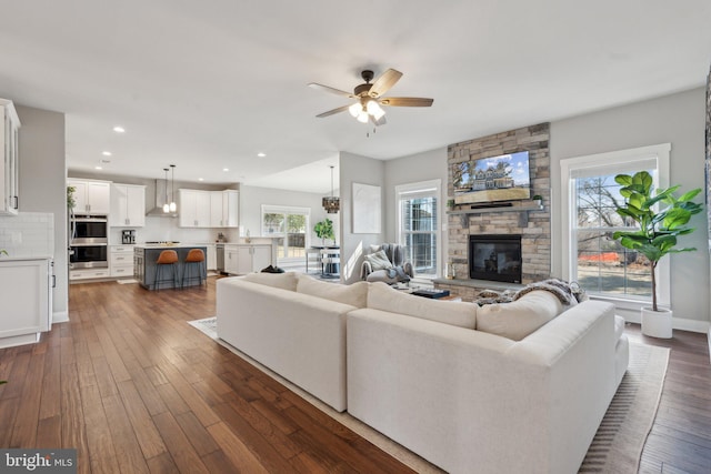 living area with dark wood-type flooring, baseboards, ceiling fan, recessed lighting, and a fireplace