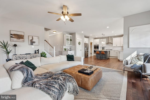 living area with recessed lighting, a ceiling fan, wood finished floors, and stairs