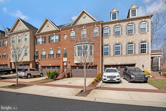 multi unit property with a garage, driveway, and brick siding