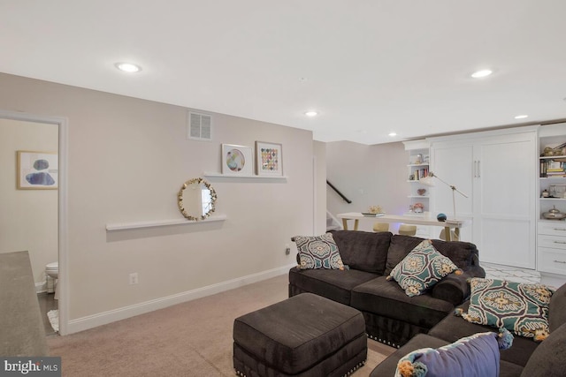 living area featuring light colored carpet, visible vents, baseboards, and stairs