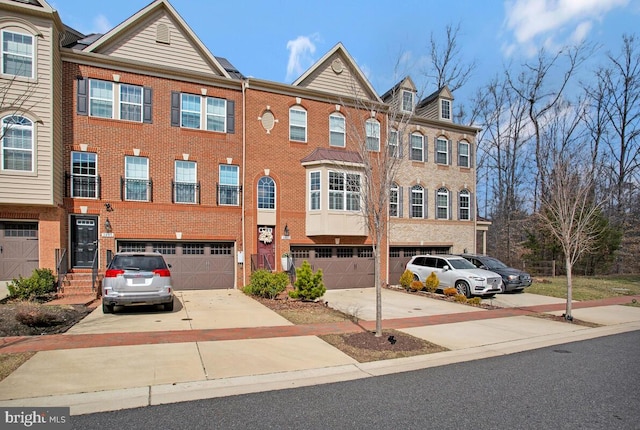 multi unit property featuring brick siding, driveway, and an attached garage