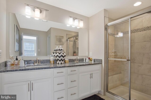 bathroom featuring double vanity, a shower stall, and a sink