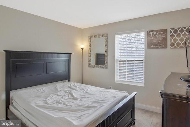 bedroom featuring light carpet and baseboards