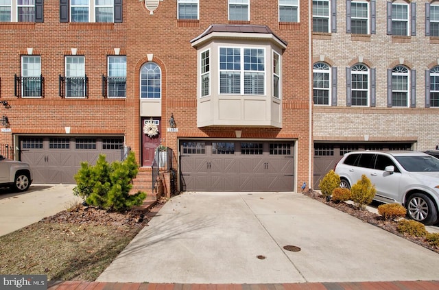 townhome / multi-family property with a garage, concrete driveway, and brick siding