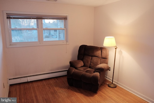 living area featuring baseboards, visible vents, baseboard heating, and wood finished floors