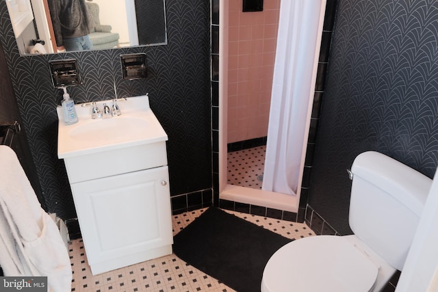 full bathroom featuring toilet, wallpapered walls, a shower stall, and vanity