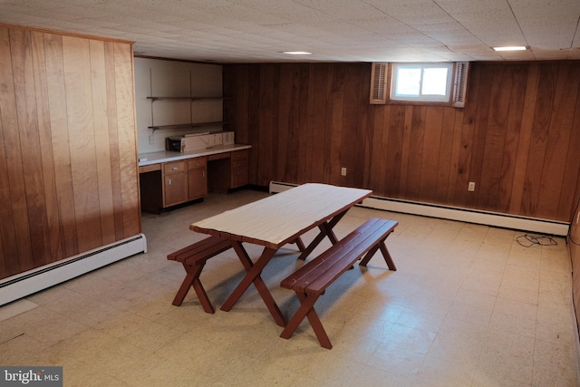 dining room with light floors, wood walls, and a baseboard radiator