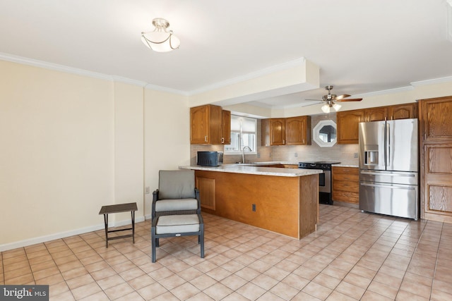 12106 Preston Dr, Lusby, MD 20657 - kitchen with crown molding, a peninsula, light countertops, brown cabinets, and stainless steel appliances